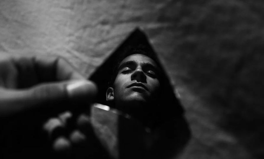 reflection of a man in a shard of broken mirror