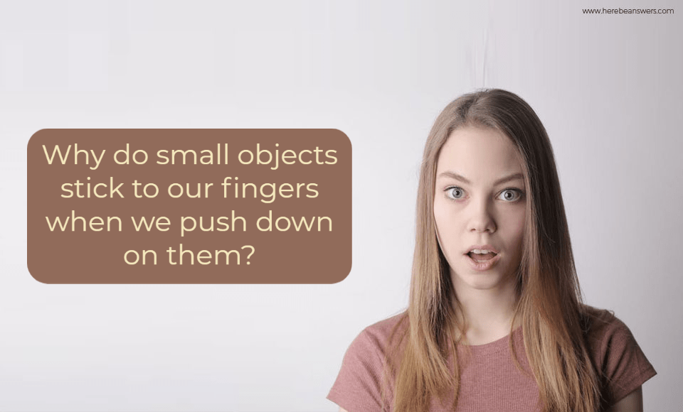Why do small objects stick to our fingers when we push down on them?