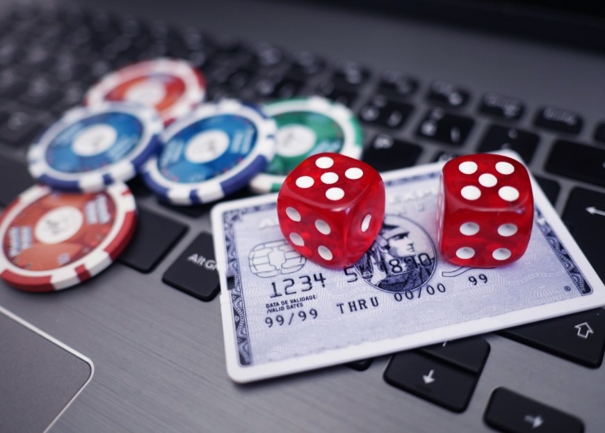 Casino card, red dice and blue chips on a laptop