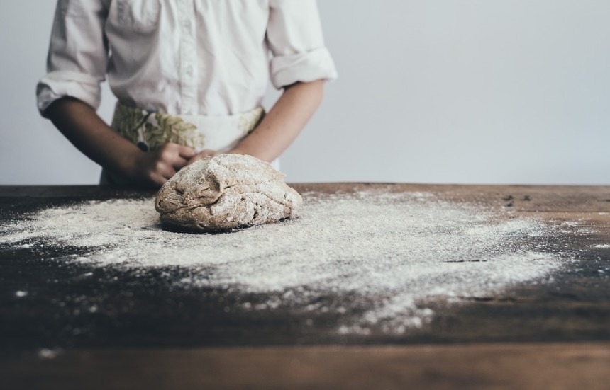 a baker standing and a dough on the table