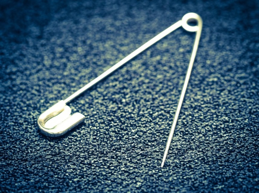 safety pin lies flat on a blue surface