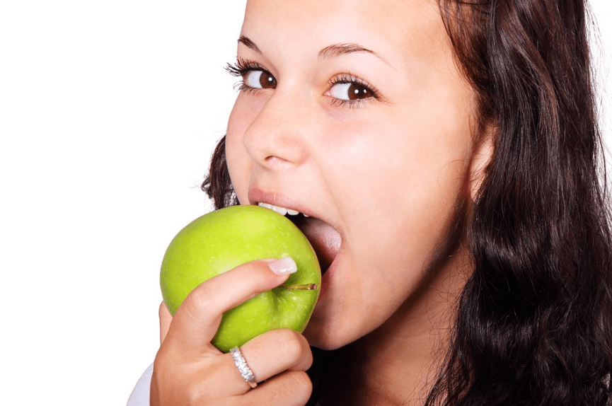 a woman biting a green apple