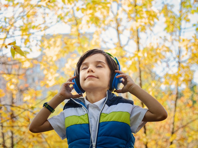a child with eyes closed while  listening in headphones