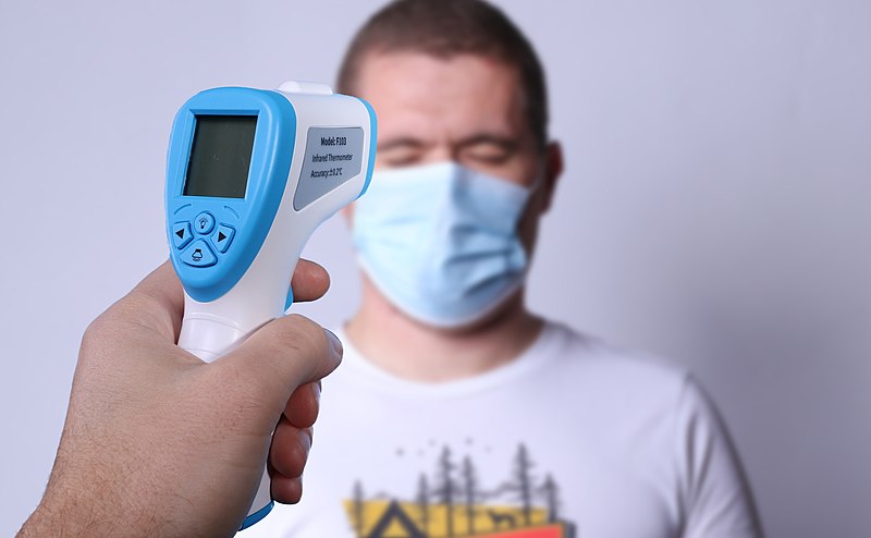 Hand-holding non-contact infrared thermometer checking a person’s temperature. COVID-19 Concept